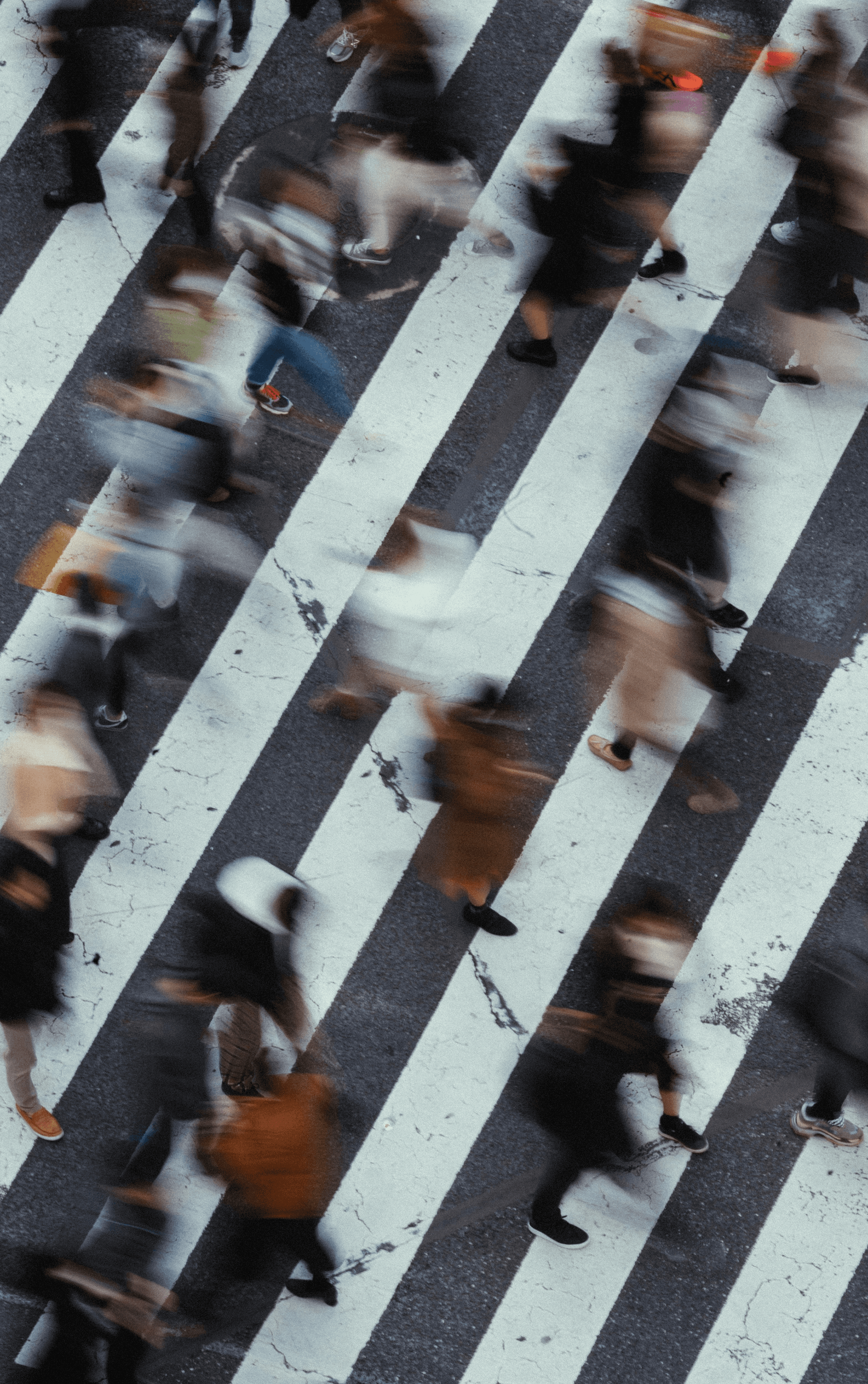 Blurred pedestrians walking across a zebra crossing, photographed from above.