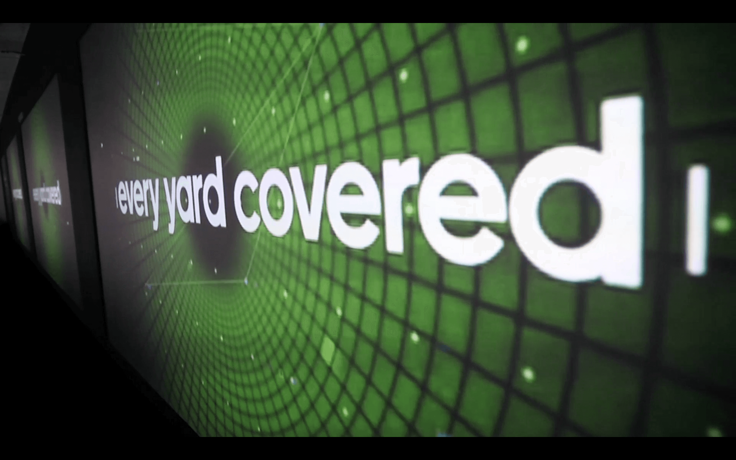 The image features an abstract design with the phrase "every yard covered," displayed in bold white letters against a dynamic green background with a grid pattern and radial pulse effect.