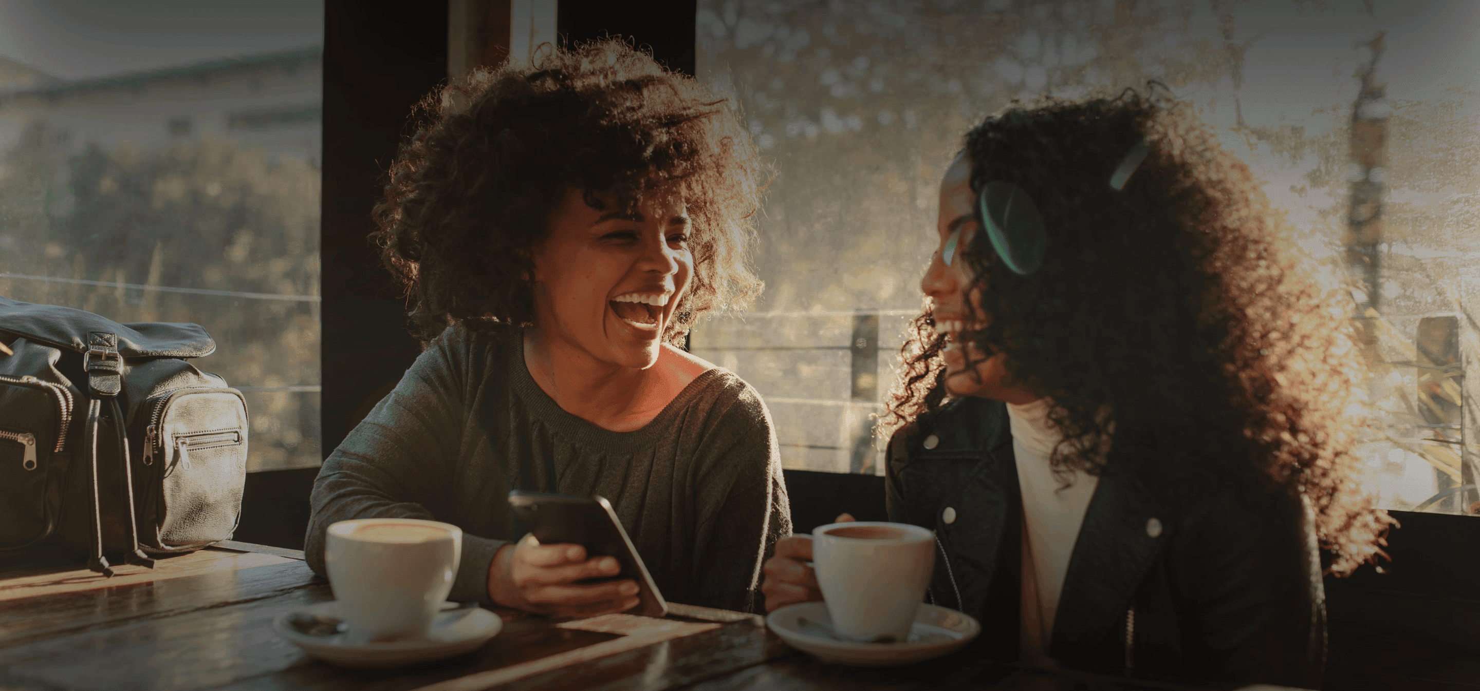 Two young black women laughing in a coffee shop