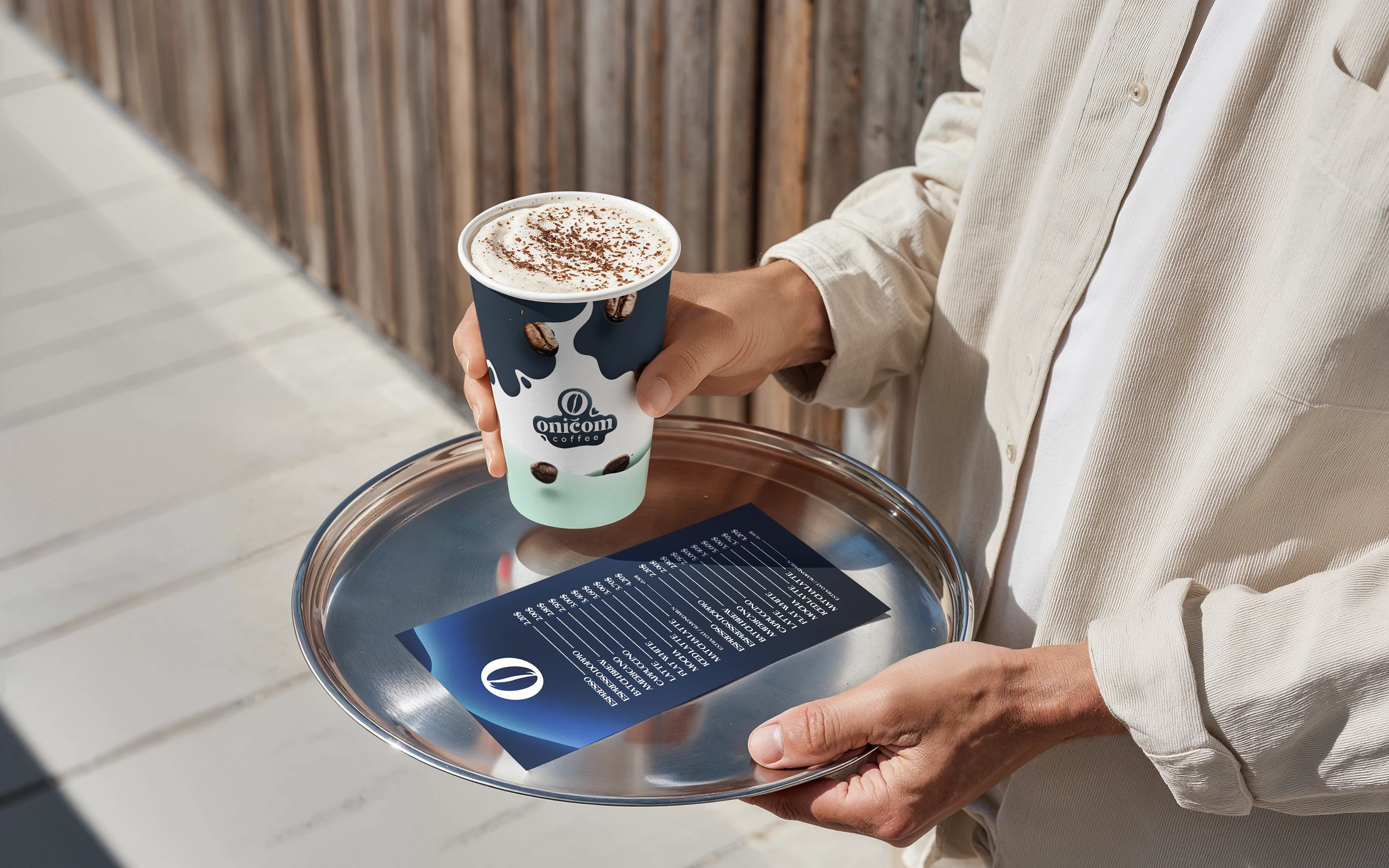 Hands holding a tray with an O Ničom branded coffee cup and card.