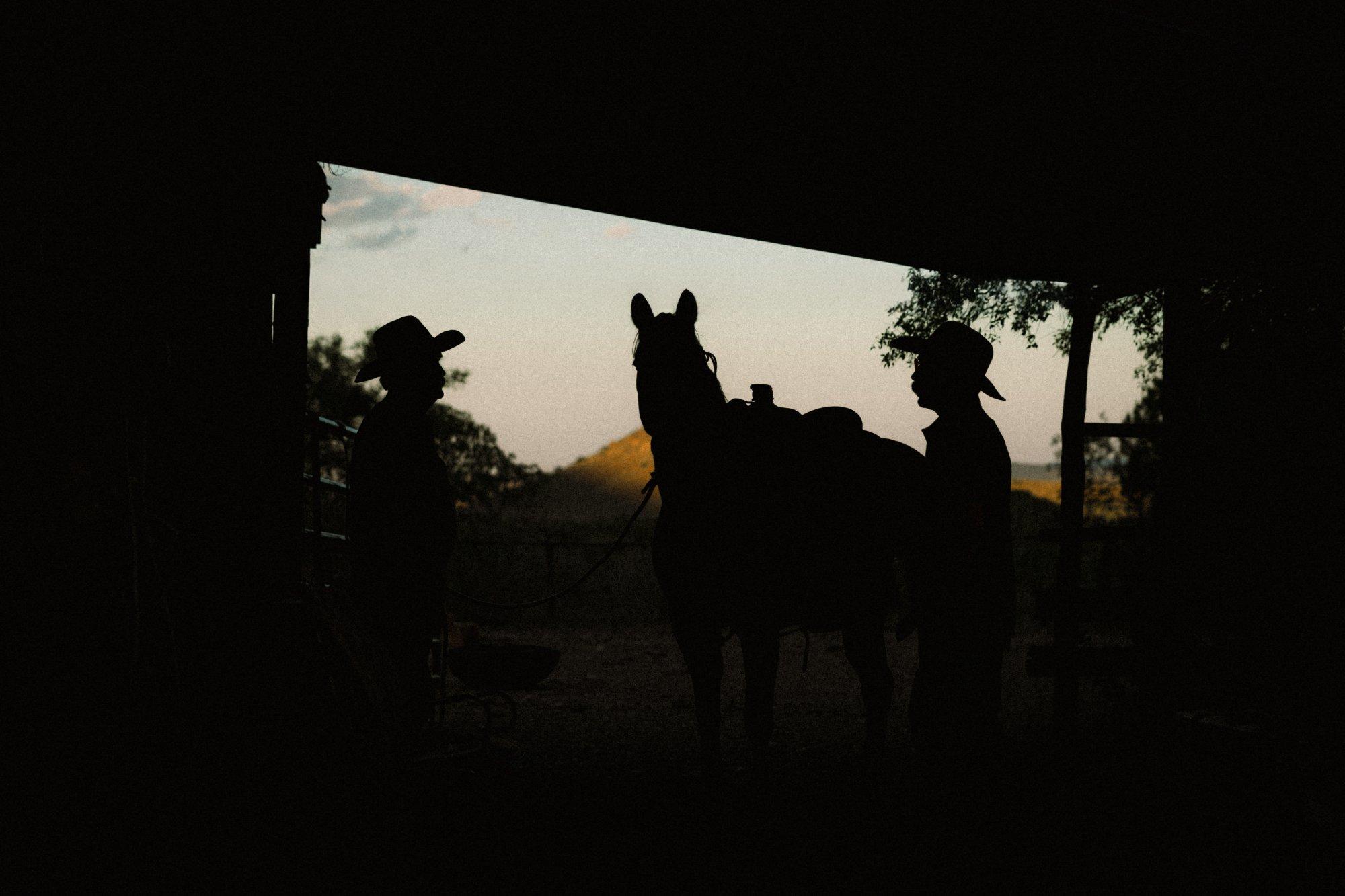 a silhouette of a horse and two cowboys
