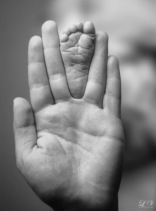 Black and white tiny baby hand against an adult hand