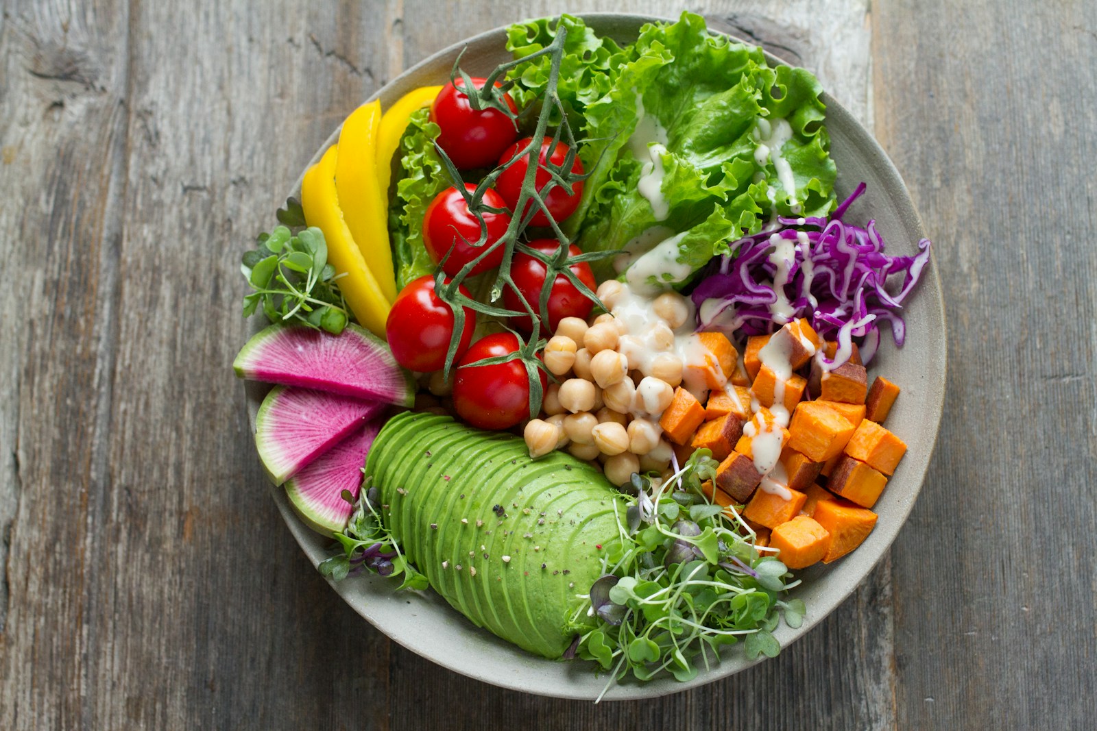 A balanced fertility-friendly plate with avocado, cherry tomatoes, chickpeas, sweet potato, and leafy greens.