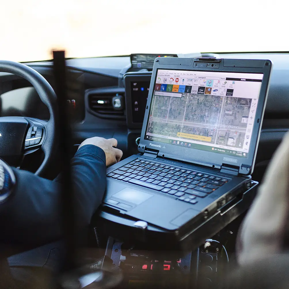 Mounted in-car workstation with rugged tablet, radio control head, and integrated communication equipment in a patrol vehicle
