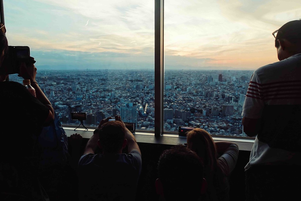 Tourist photgraphing the sunset in Tokyo from a highrise building