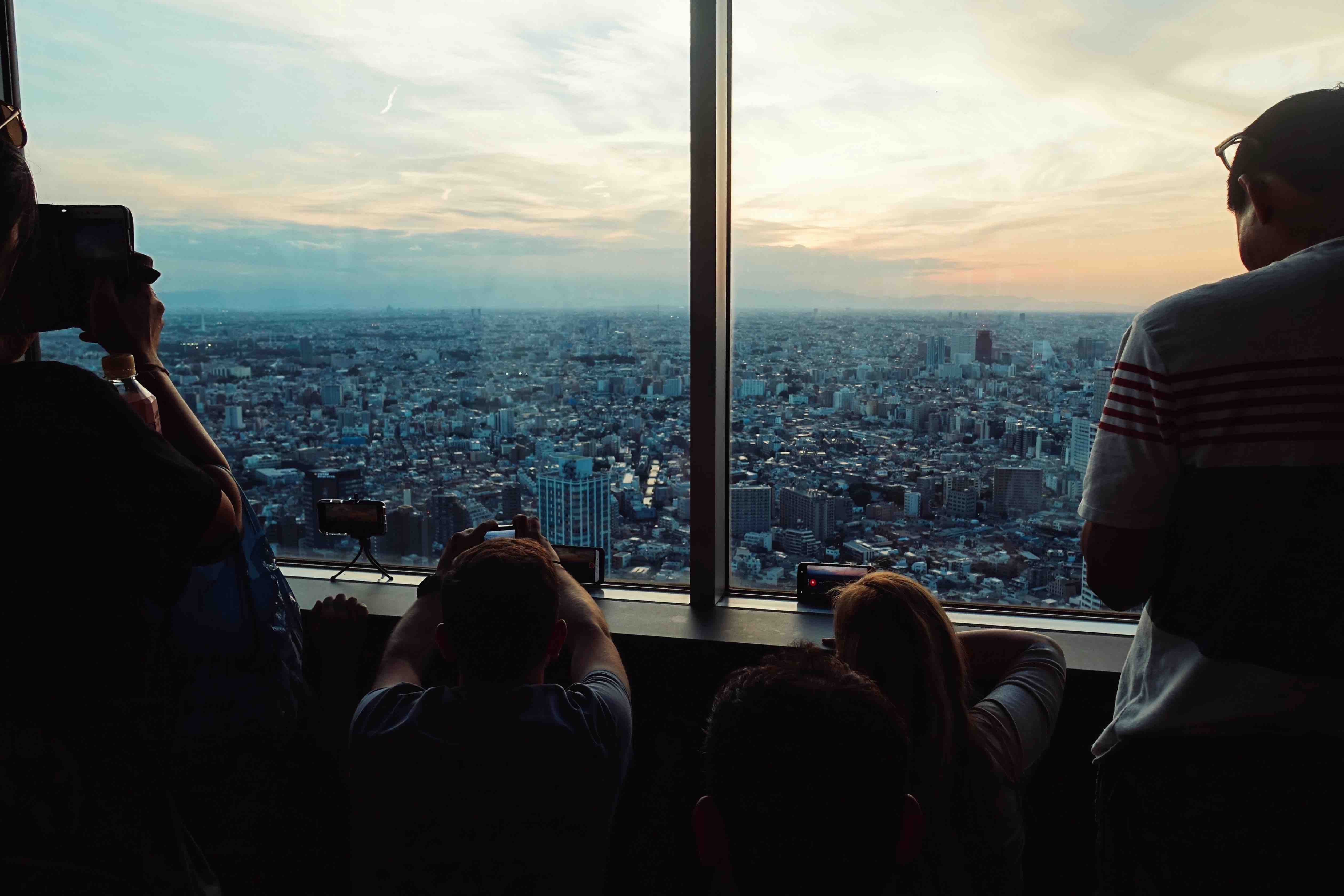 Tourist photgraphing the sunset in Tokyo from a highrise building