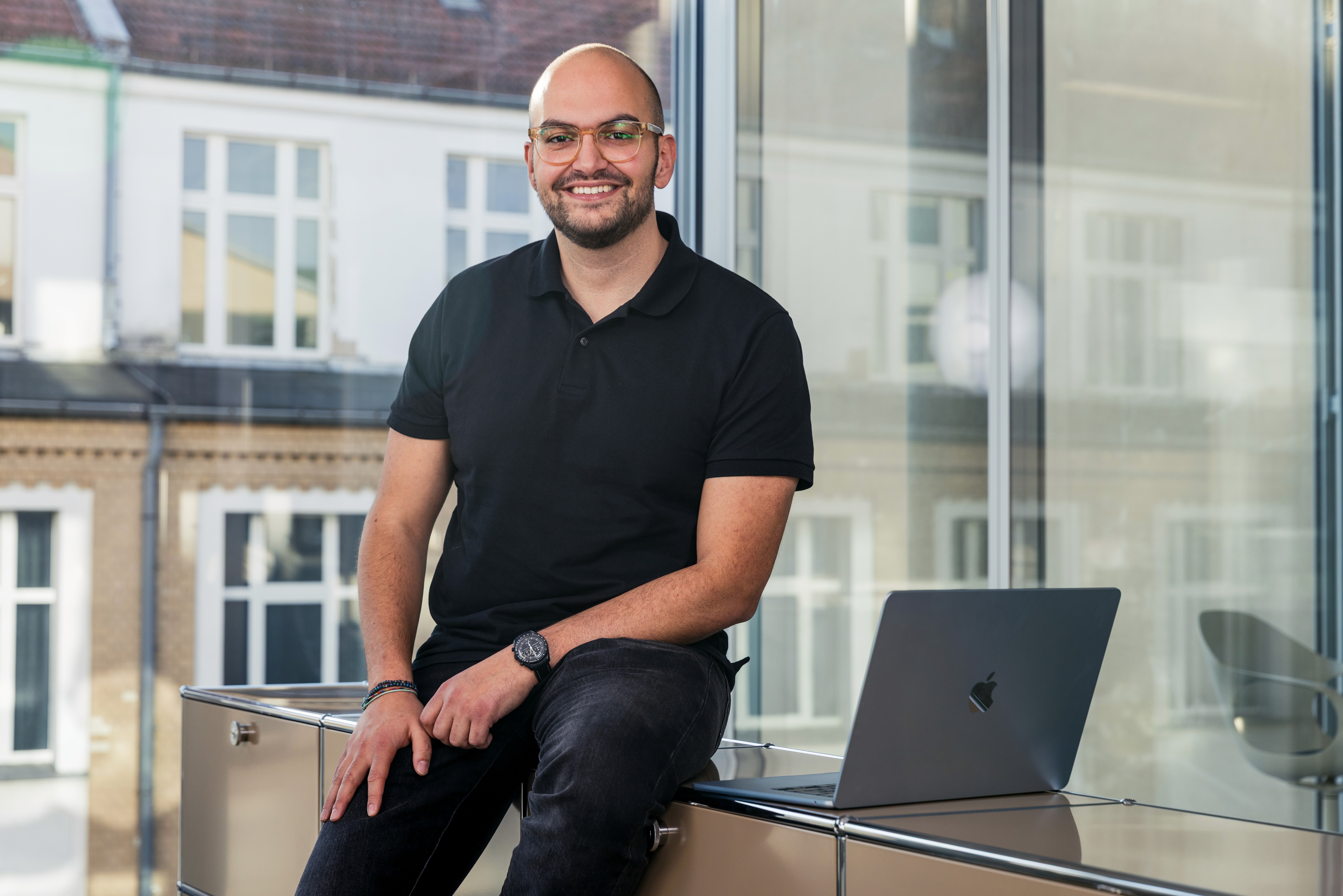 Nabil el Berr., CEO von Indicium, sitzt mit einem Laptop im Büro und blickt in die Kamera und lächelt.