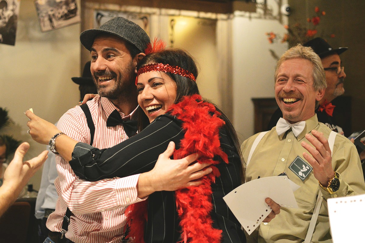 A group of people dressed as pirates sit on stairs and take selfies during a team-building program.
