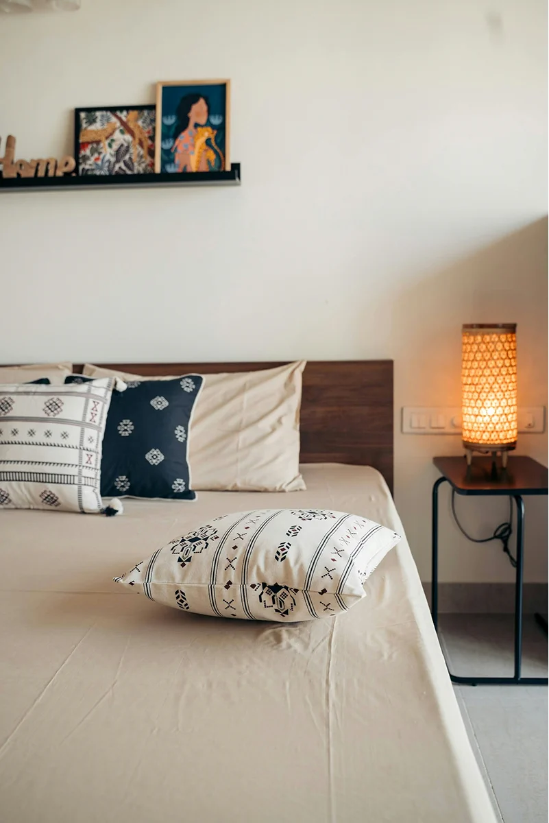 Close-up of the beachfront bungalow bed with patterned pillows and warm bedside lighting.