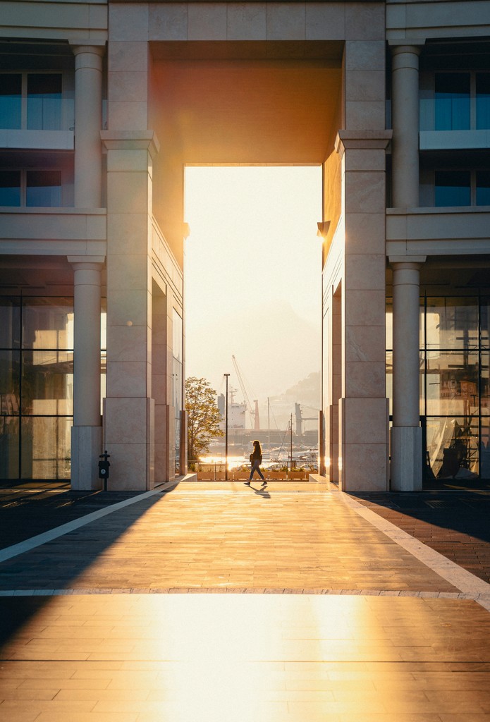 A person walking between two tan buildings before sunset