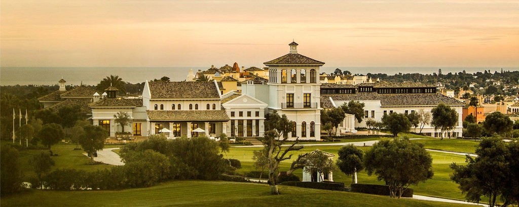 Luxury Spanish villa resort overlooking a lush green golf course at sunset.