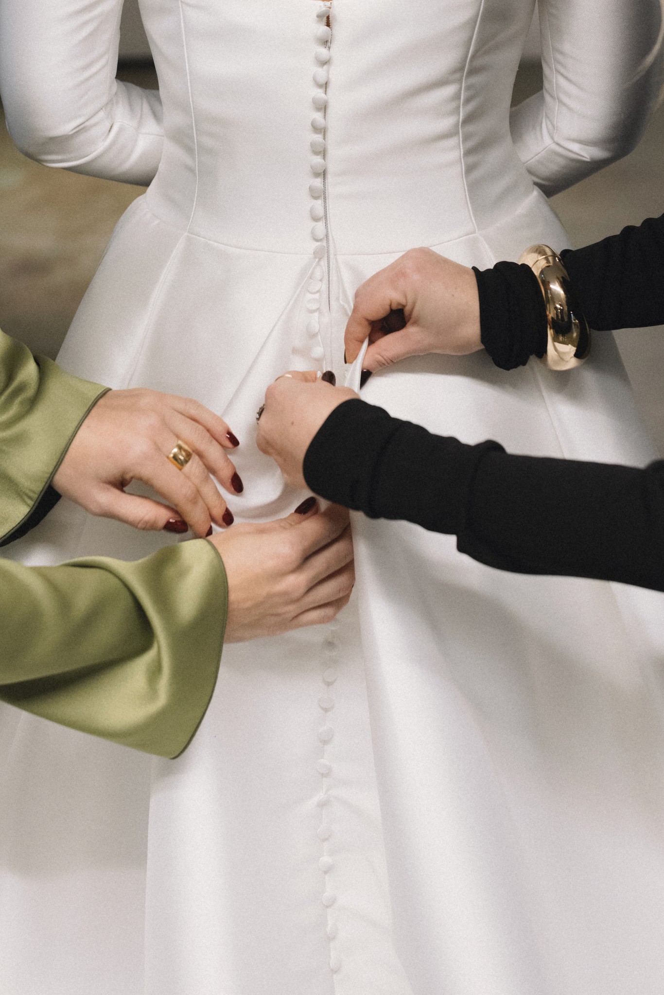 Sposa in abito mikado bianco con bottoni, mani degli sposi che si toccano durante i preparativi del matrimonio a Parma