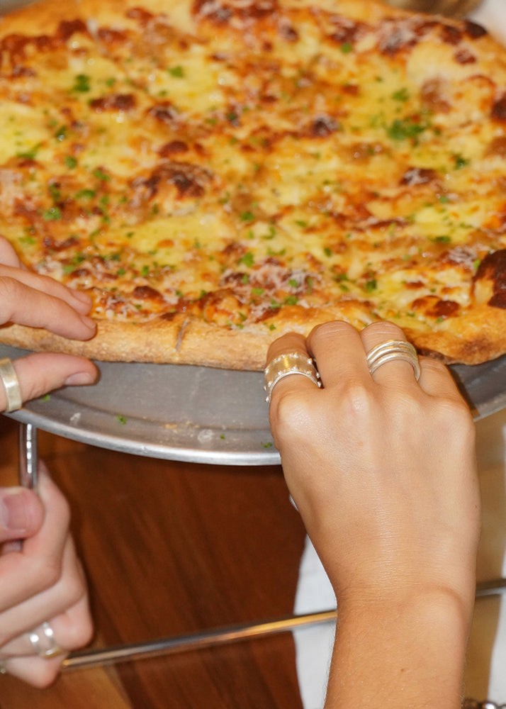 Person holding a pizza with a close-up of the crust and cheese