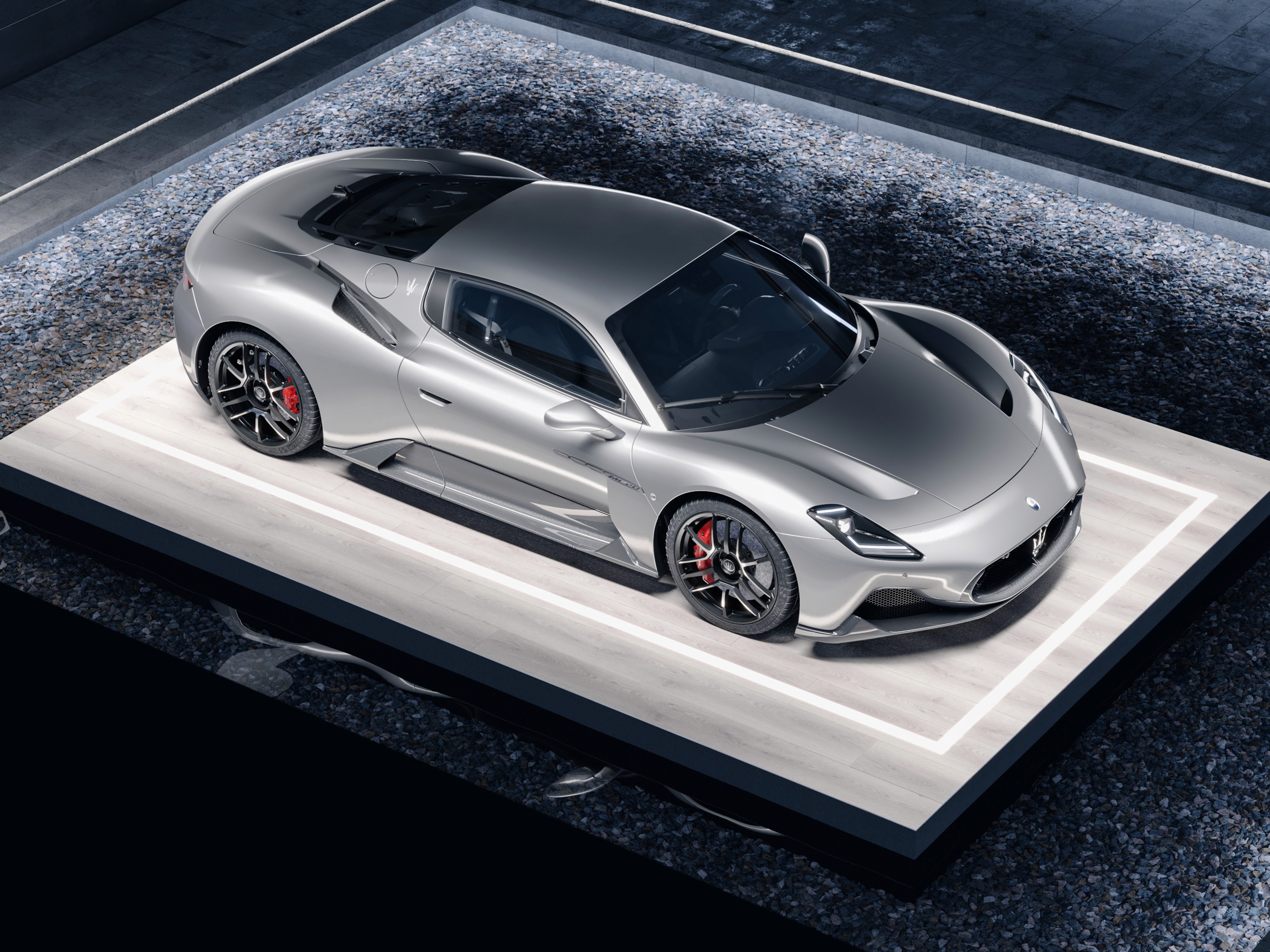 Visualizzazione 3D di Maserati MC20 con carpaint argento, cerchi neri e pinze freno brembo rosse. La macchina poggia su una piattaforma in marmo.