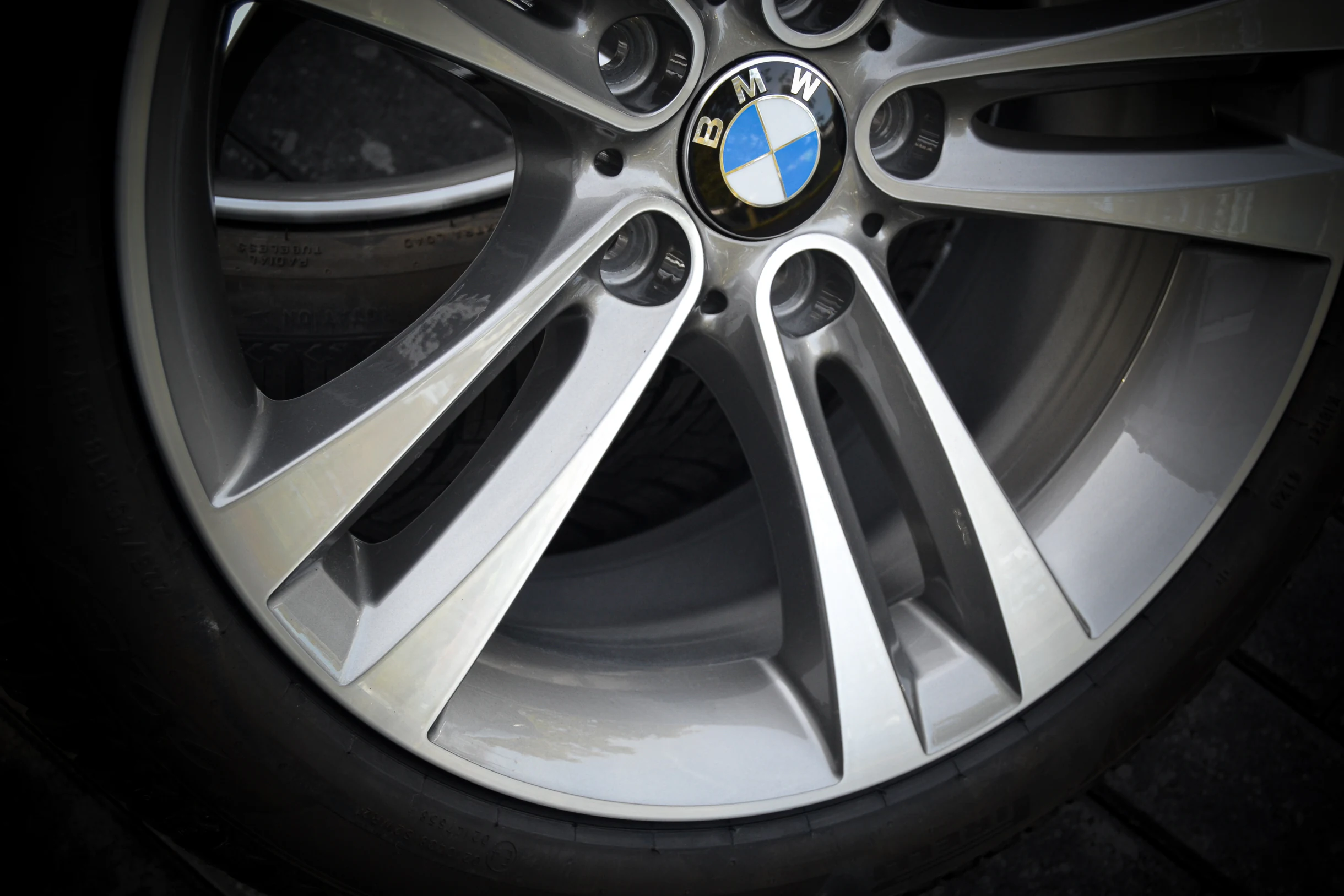 Nahaufnahme der silberfarbenen Speichenflächen und des äußeren Felgenrands einer BMW-Felge bei AT Plus.