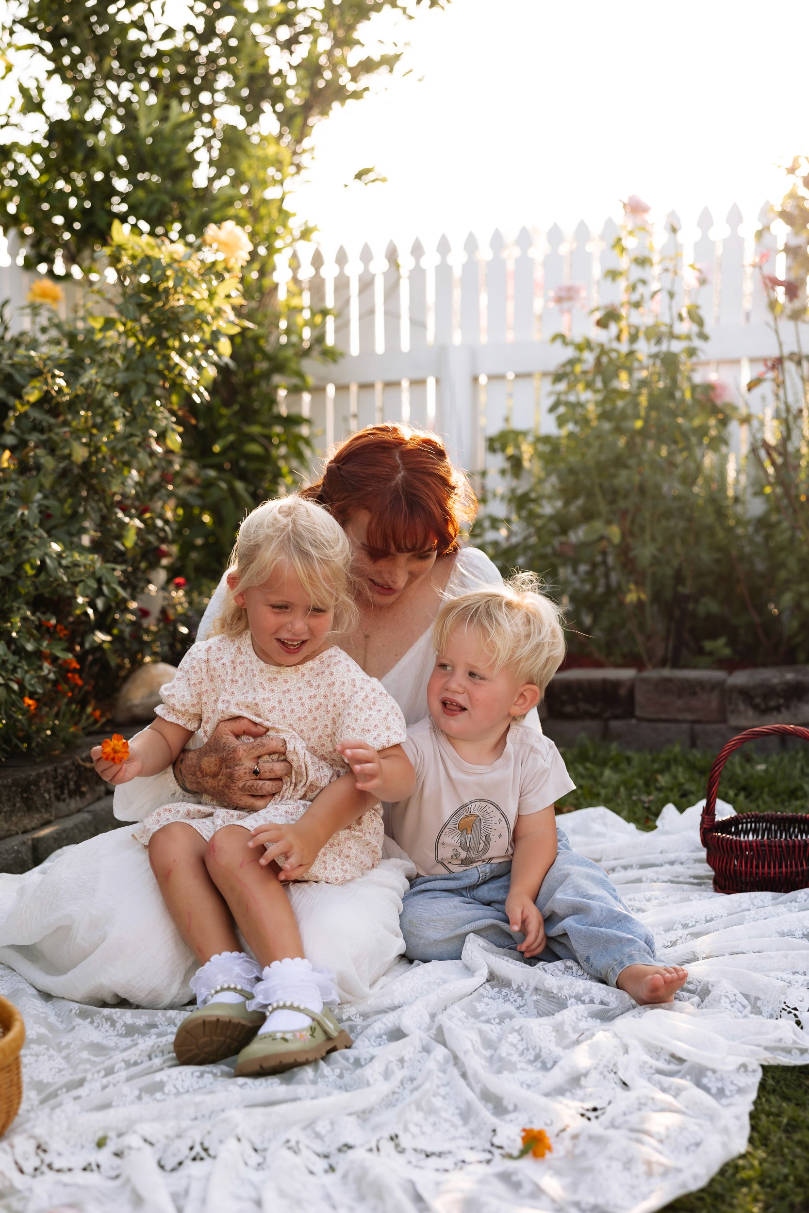 Mother sitting with two young children on picnic blanket at home photoshoot in Mackay