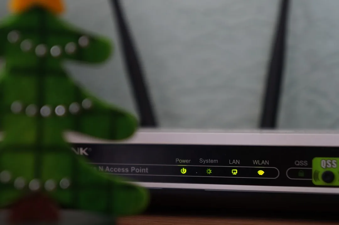 A Wi-Fi router with glowing indicator lights, partially obscured by a blurred decorative green Christmas tree in the foreground.