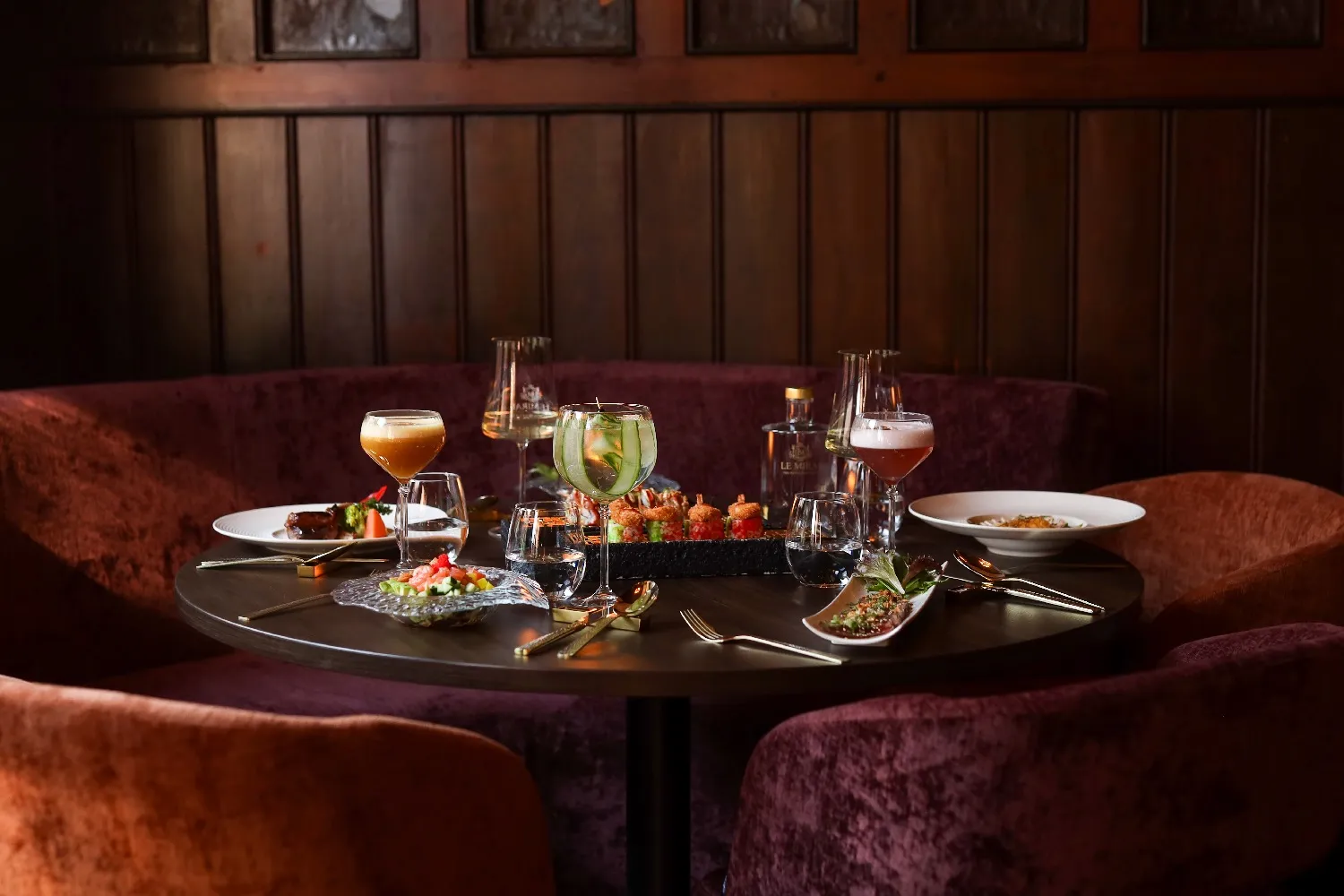 Tafel met cocktails en eten in een sfeervolle hoek van het restaurant