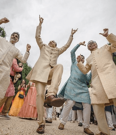 Unposed baraat celebration with guests dancing exuberantly, representing the lively spirit and festive atmosphere captured in candid wedding photography.