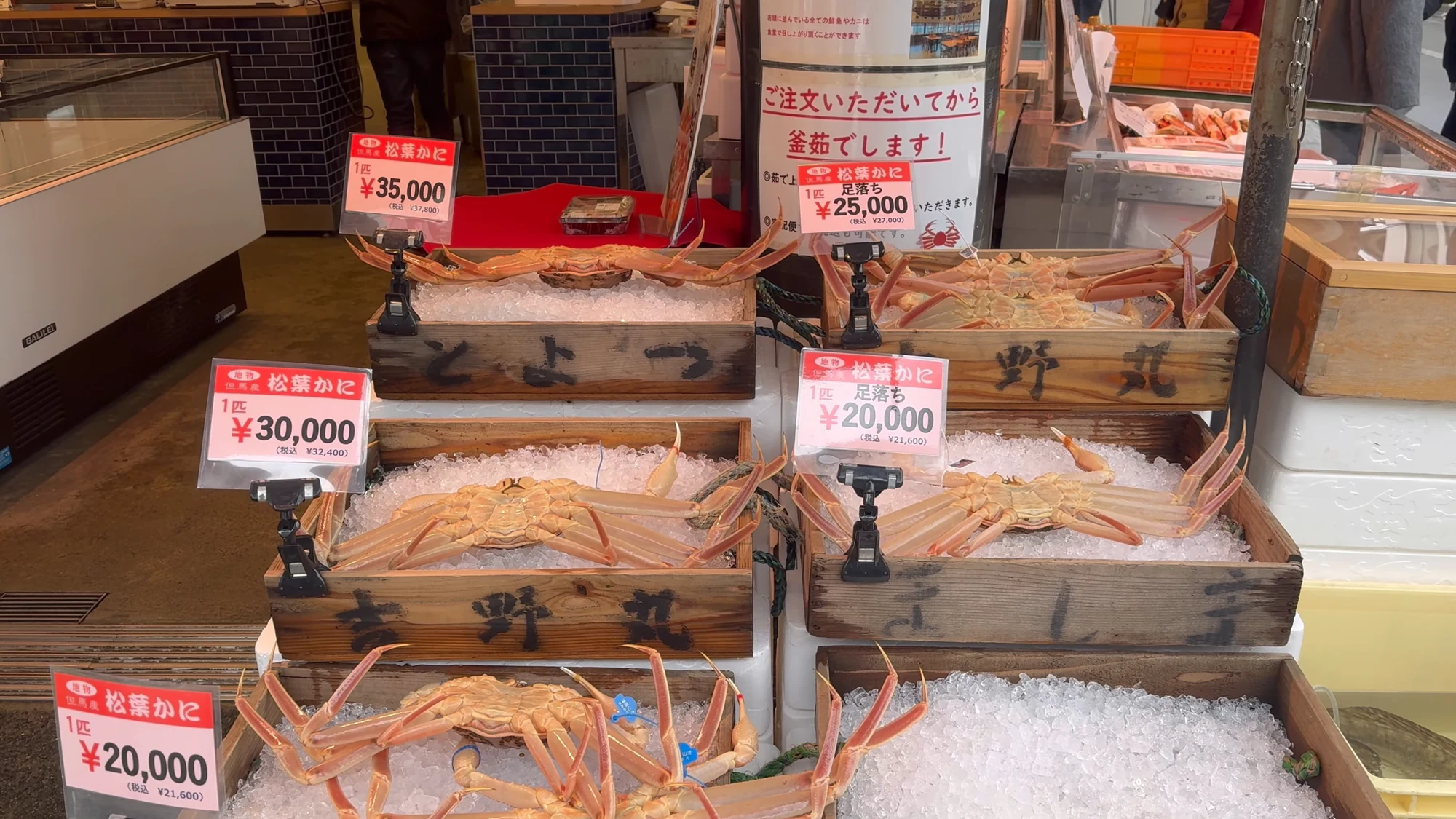 Whole snow crabs on ice in a Kinosaki shop window with price cards in yen.