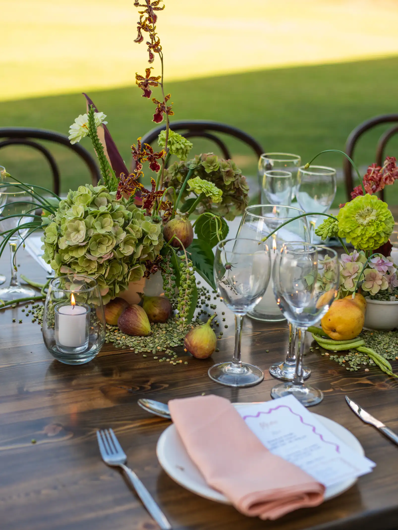 Detalle de mesa decorada con hortensias verdes y velas blancas para almuerzo elegante en entorno natural