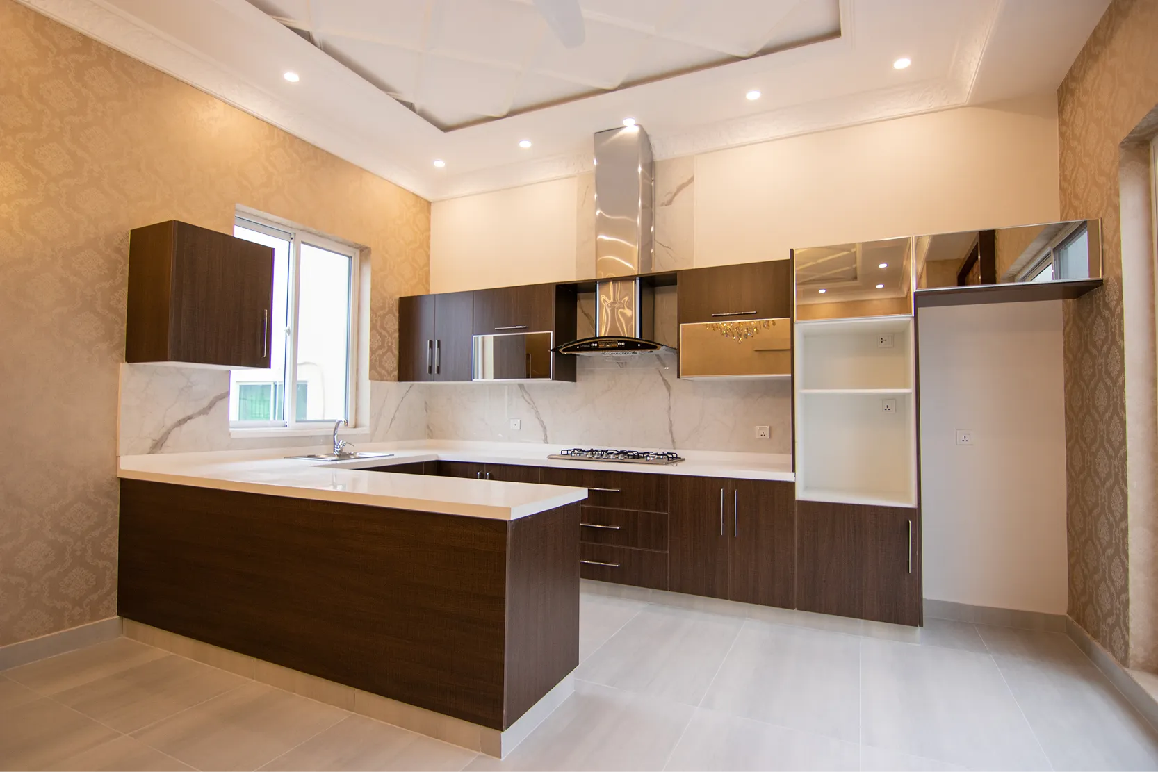 Modern kitchen interior featuring dark wood cabinets, white marble countertops, and stainless steel range hood.