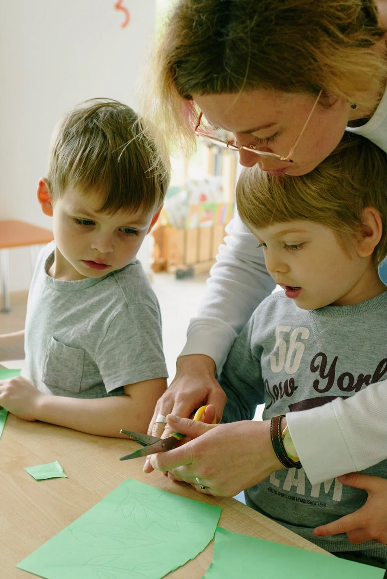 Preschool teacher supporting children during a hands-on learning activity.
