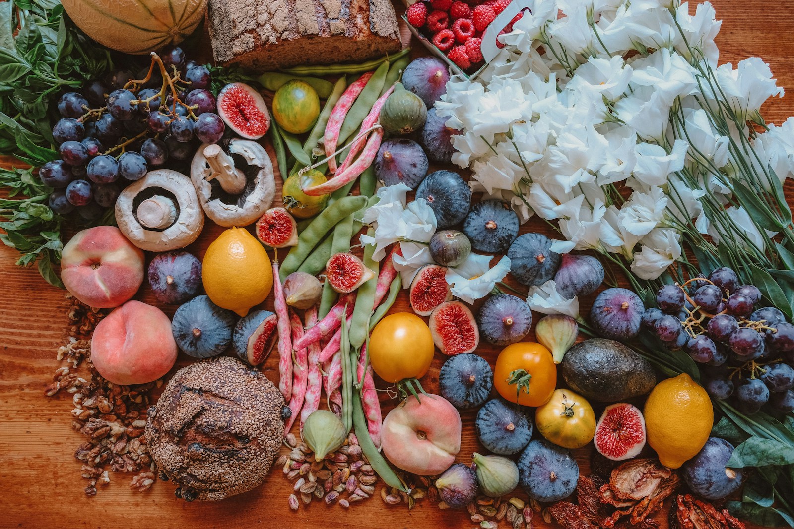 An assortment of high-fiber whole foods including fresh fruit, beans, and seeds spread on a wooden table, the mostly-plant pattern used to prevent future flares.