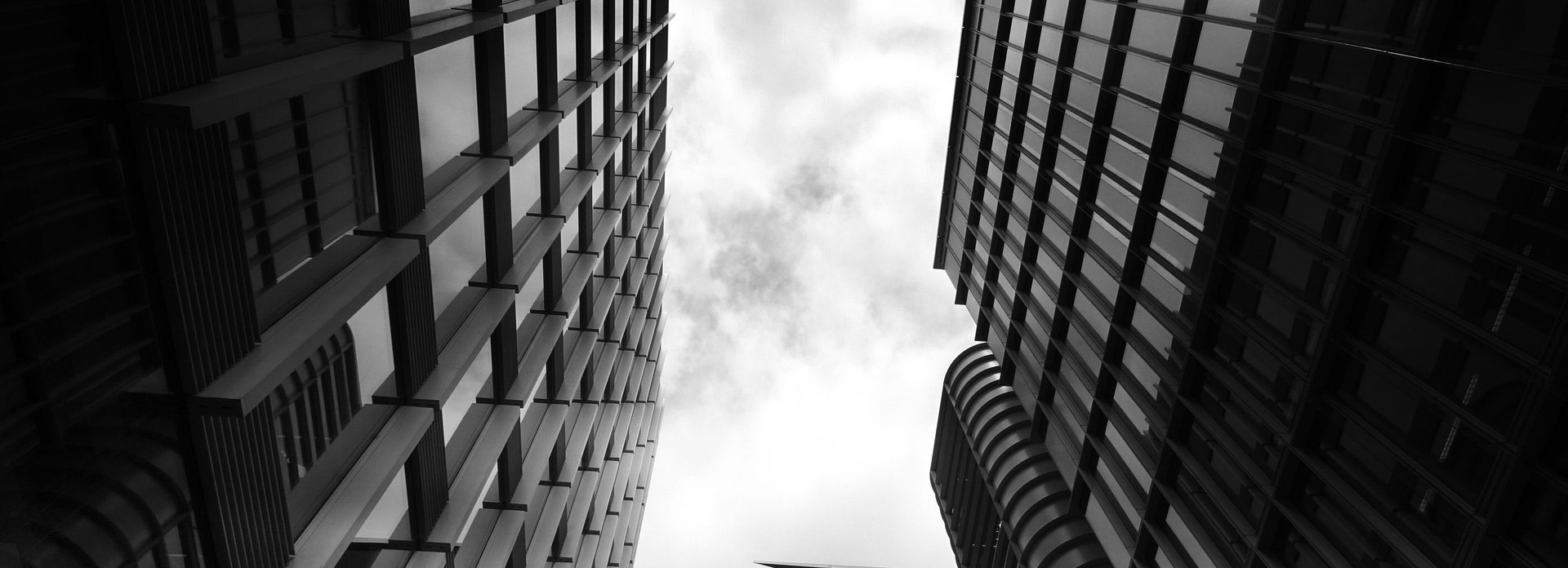 Black and white photo of a narrow alleyway between tall buildings, with bright light visible at the far end.