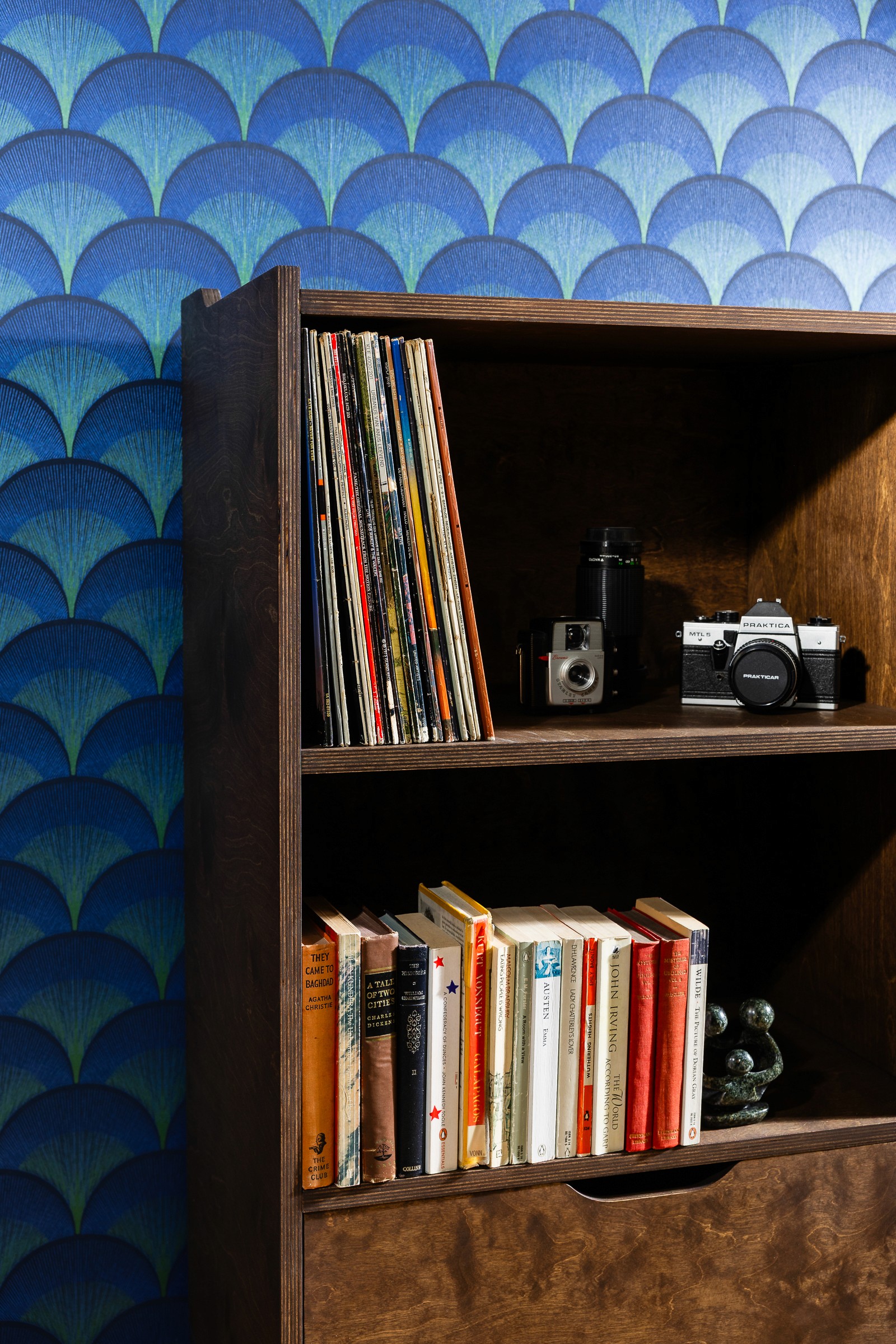 schappen in een tv-meubel gevuld met vinylplaten, oude camera's en boeken