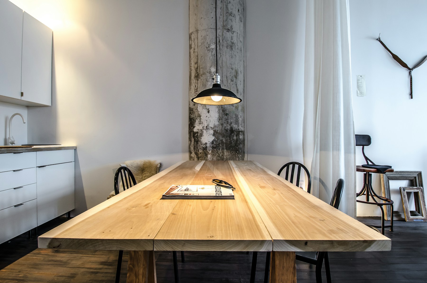 Long timber dining table under a black pendant light