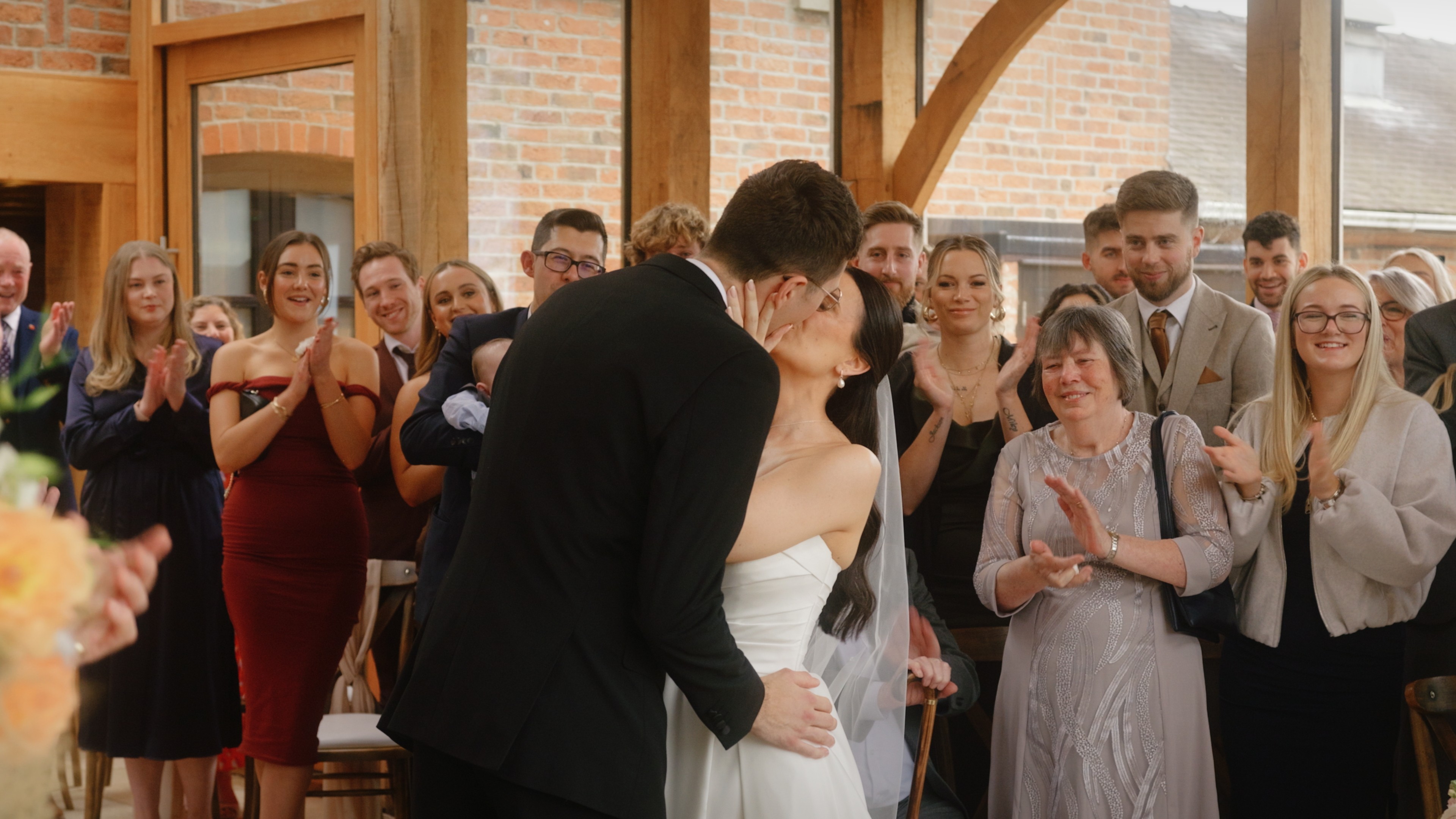 Bride and groom sharing their first kiss as newlyweds during the wedding ceremony at Swancar Farm