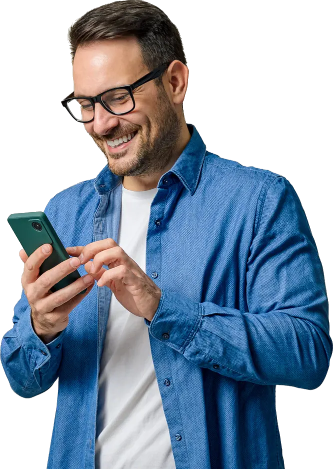 A smiling man in glasses wearing a blue shirt is looking at his smartphone.