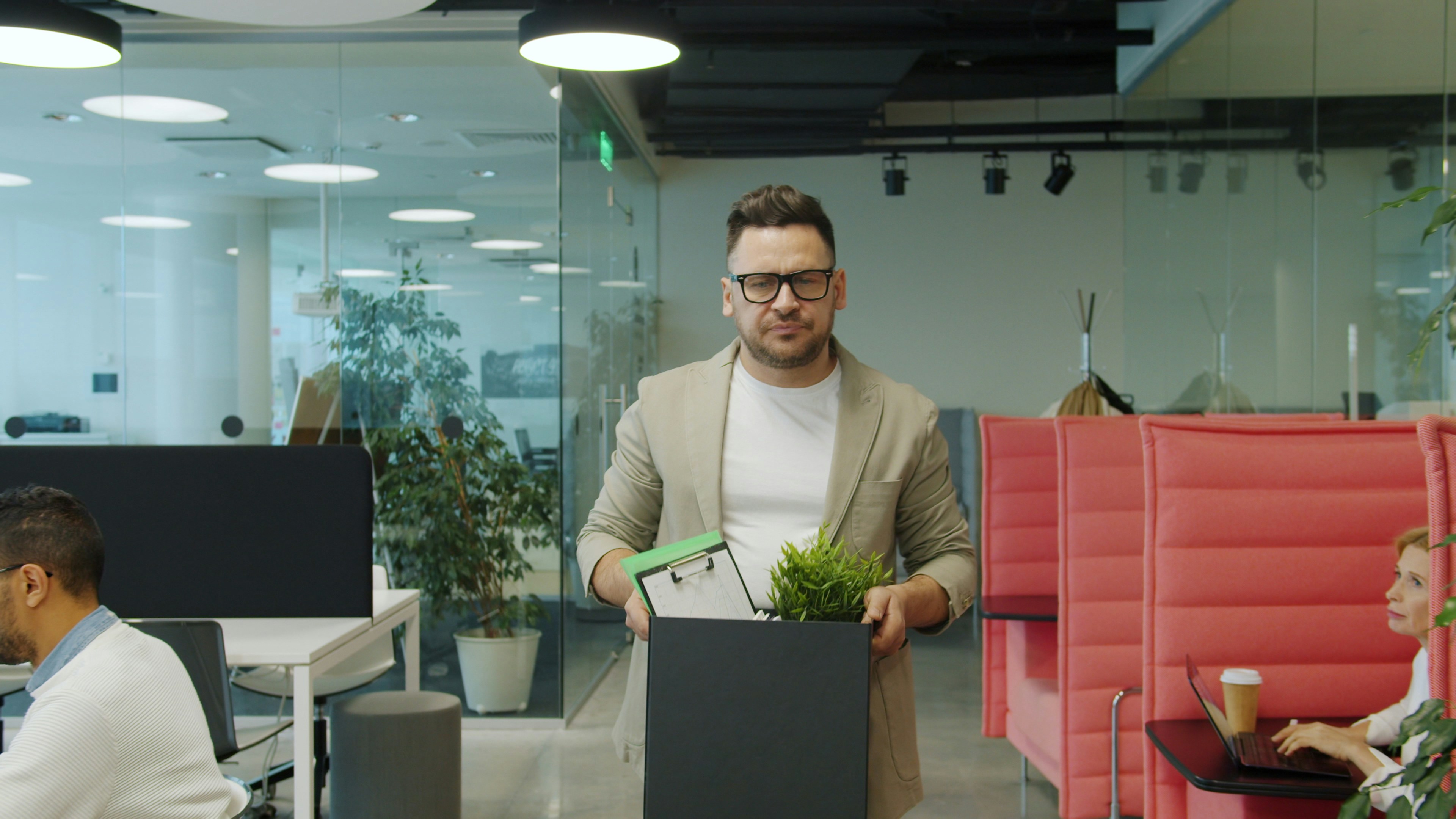 Man holding a box with his office/desk items on as he looks to move offices