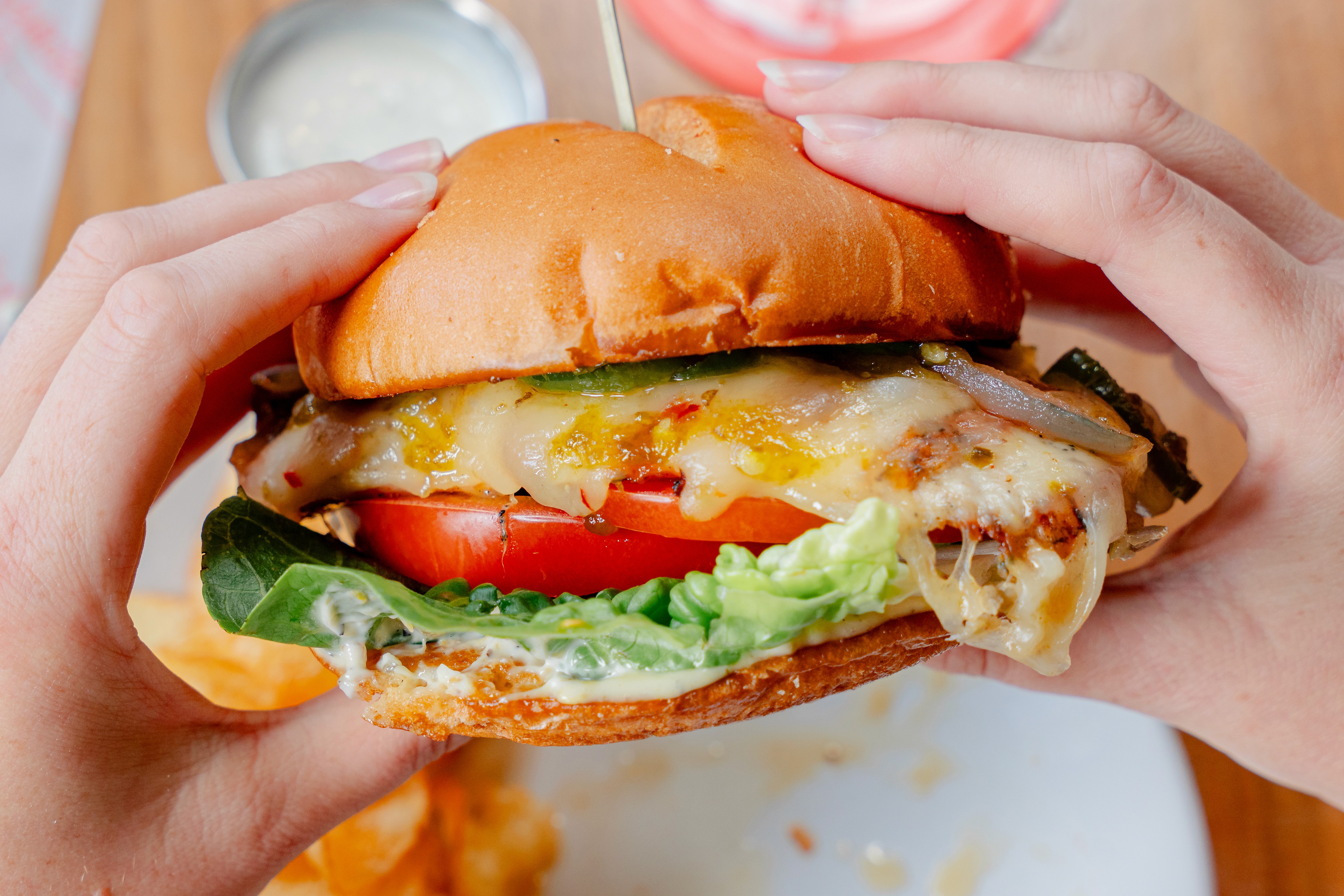 Hands holding a grilled chicken sandwich