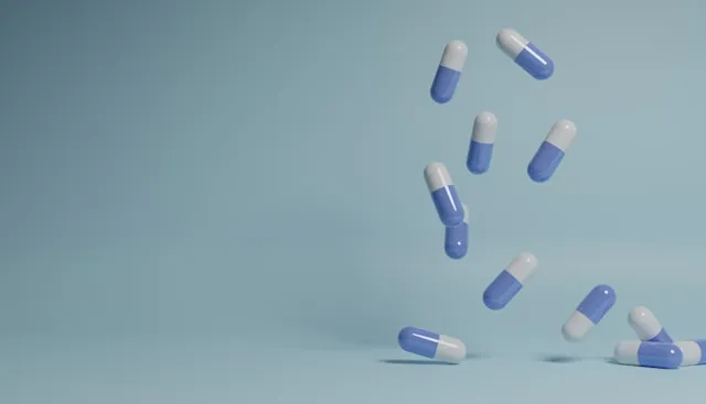 Blue and white capsules falling on a light blue background