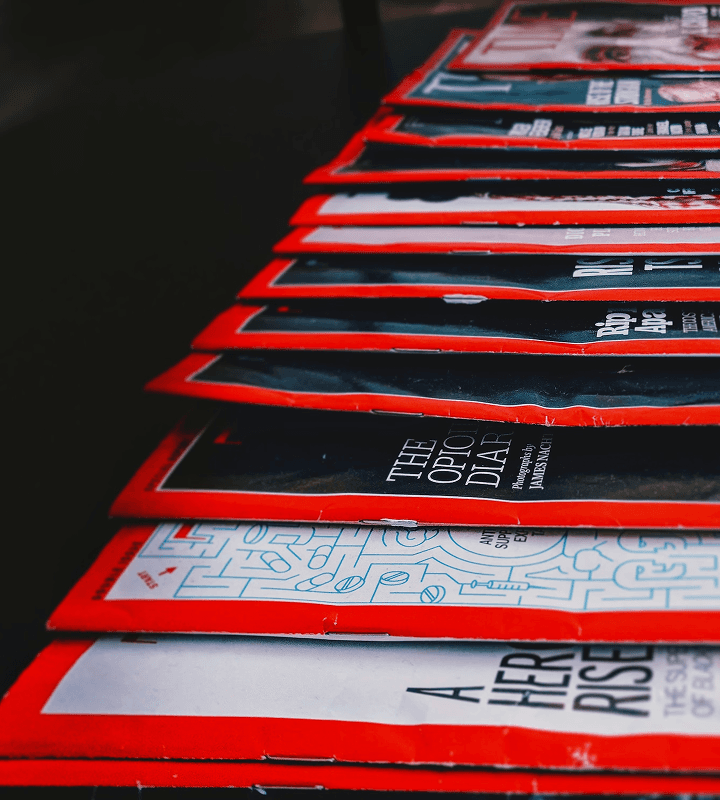 A stack of magazines with red borders arranged in a row, viewed from a low angle.