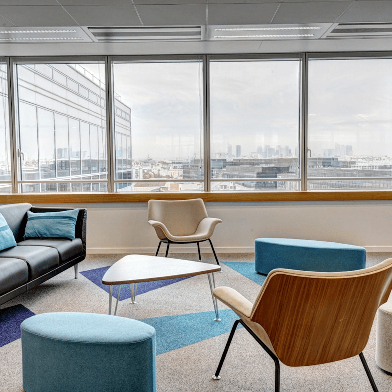 Free Framer Template - Modern lounge area with colorful chairs and a coffee table, featuring large windows with a city view.