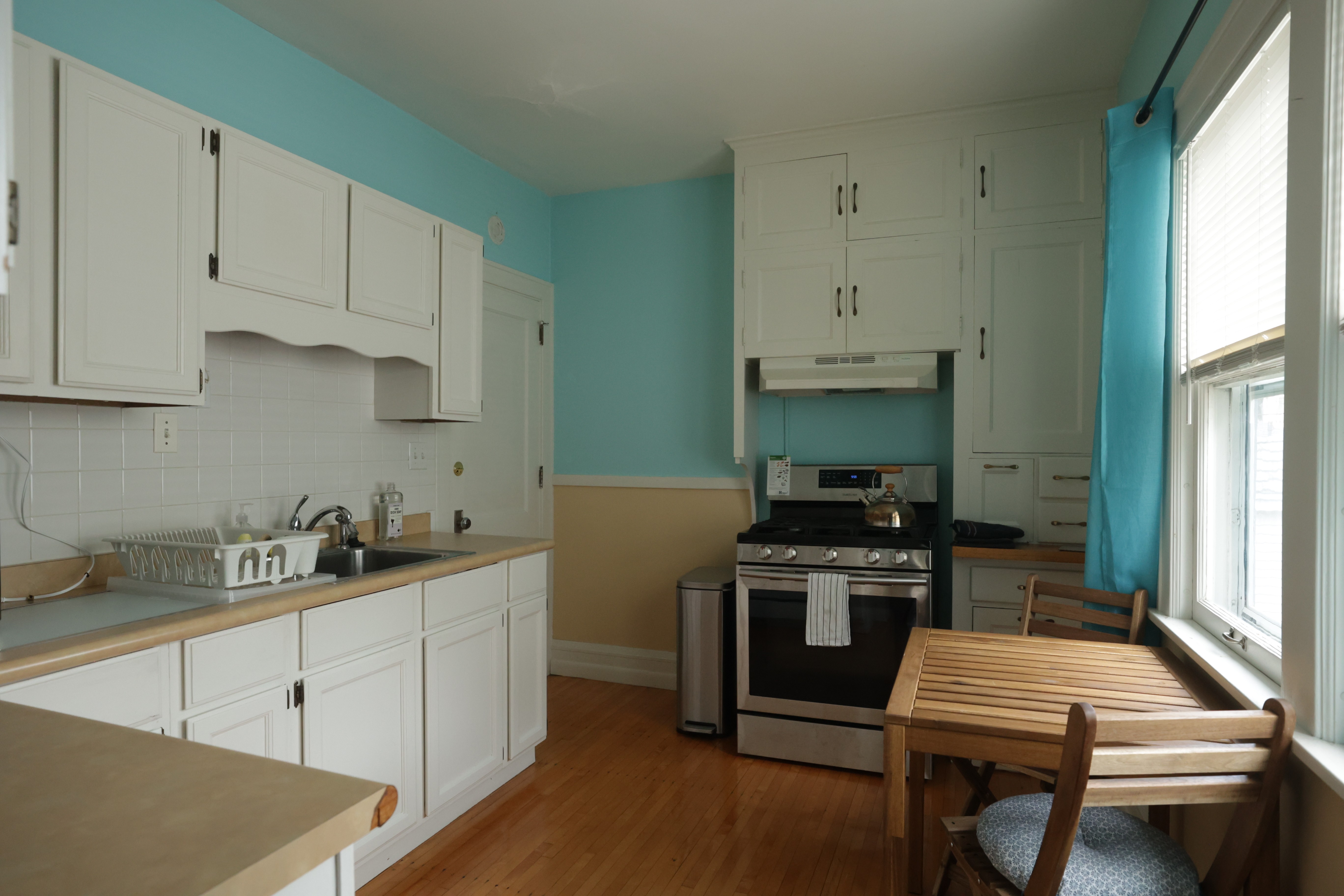 Cozy kitchen with light blue walls, white cabinetry, and a small dining table set.