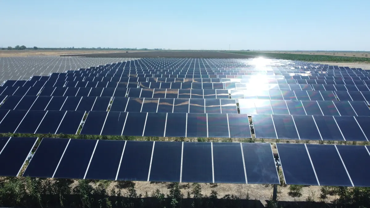 Drone view over a ground-mount solar field with sun glare on the panels at Madera Winery in Madera, CA