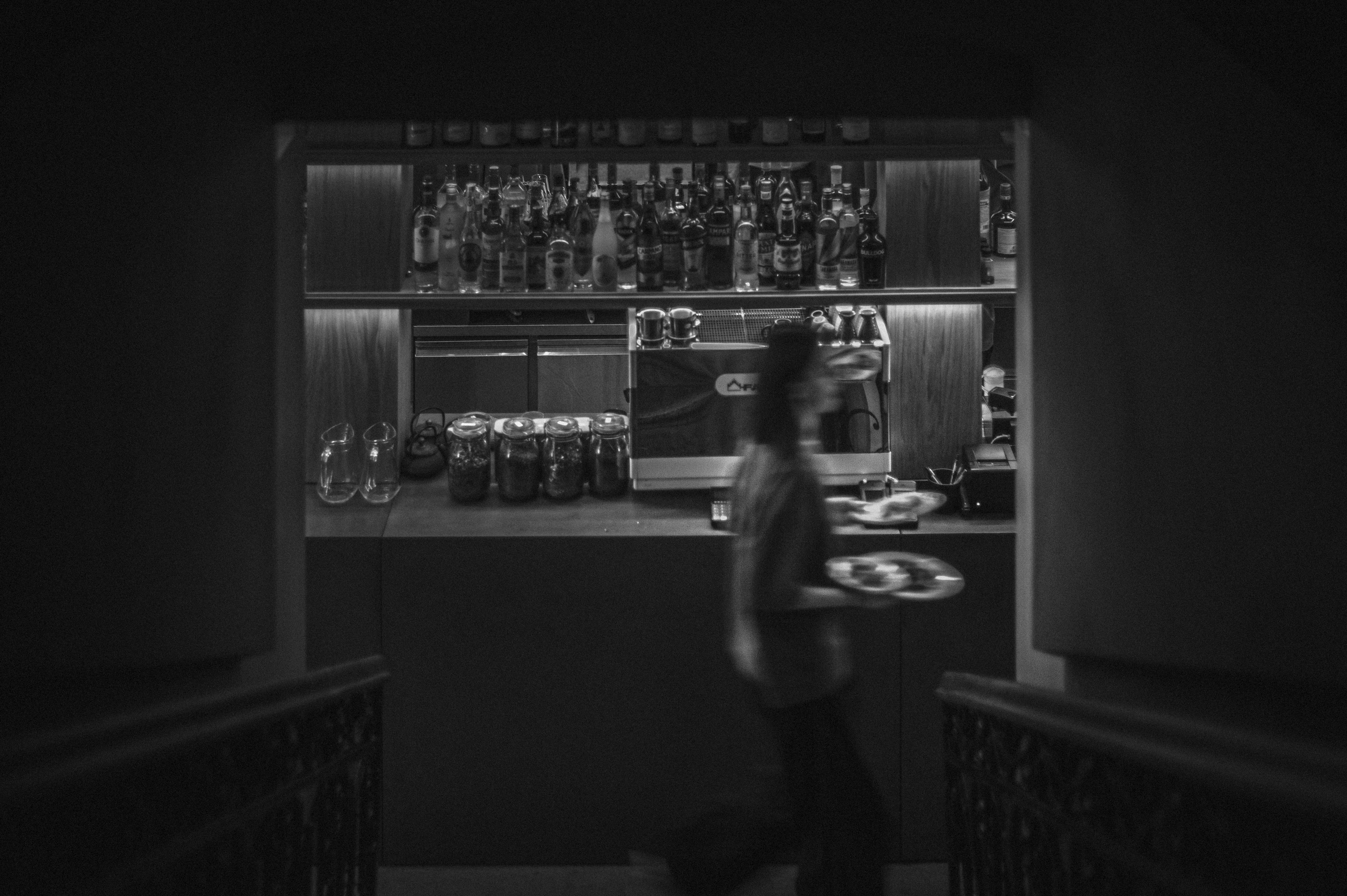 A man walking down a dark hallway next to a bar