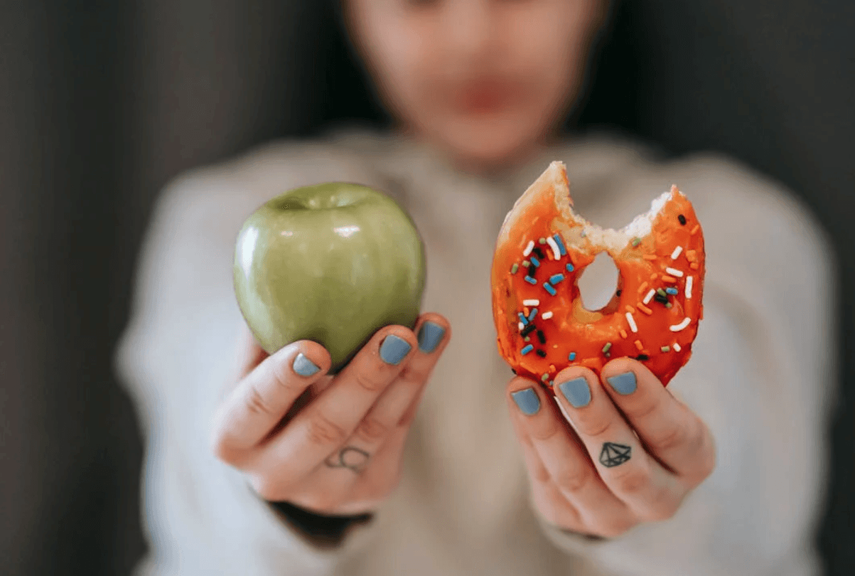 Femme tenant une pomme et un beignet