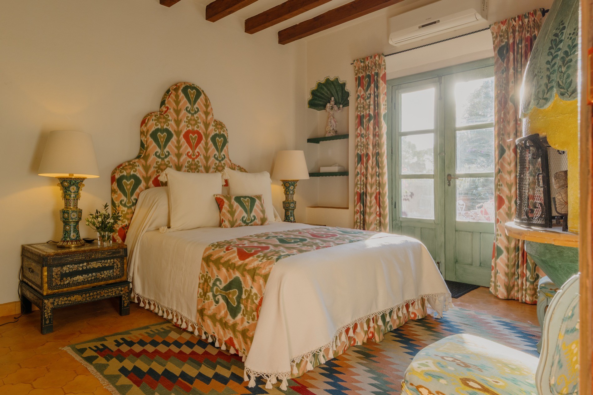 La Residencia guest bedroom with ikat headboard, kilim rug, and painted Mexican fireplace