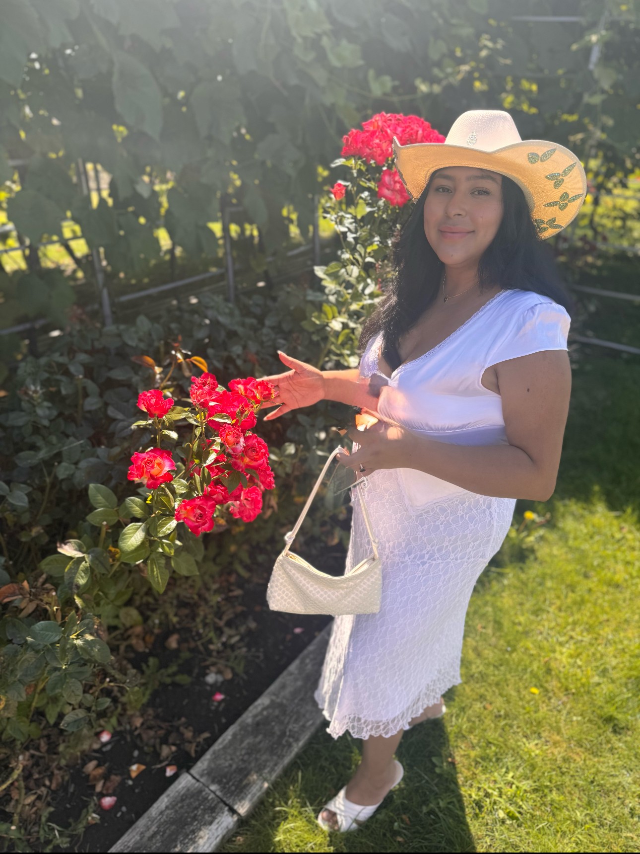 Vanessa, CEO of Pretty Little Things in a garden  of roses. she's wearing white.