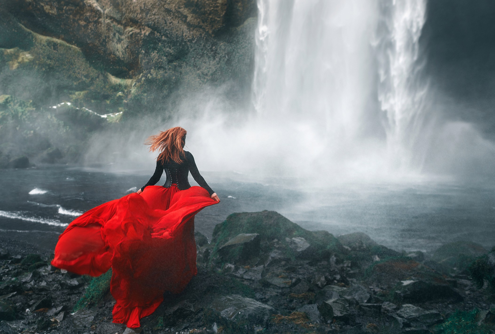 woman by a waterfall with bright red long skirt