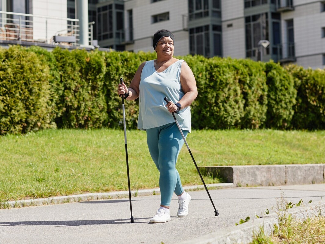 older woman walking with aids to learn how to start running to lose weight with low fitness levels