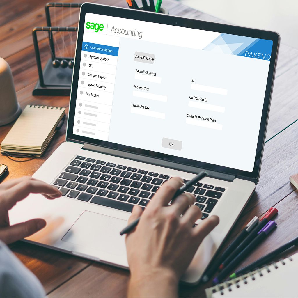 Person typing on laptop showing Sage Accounting settings with PaymentEvolution payroll configuration options including tax tables