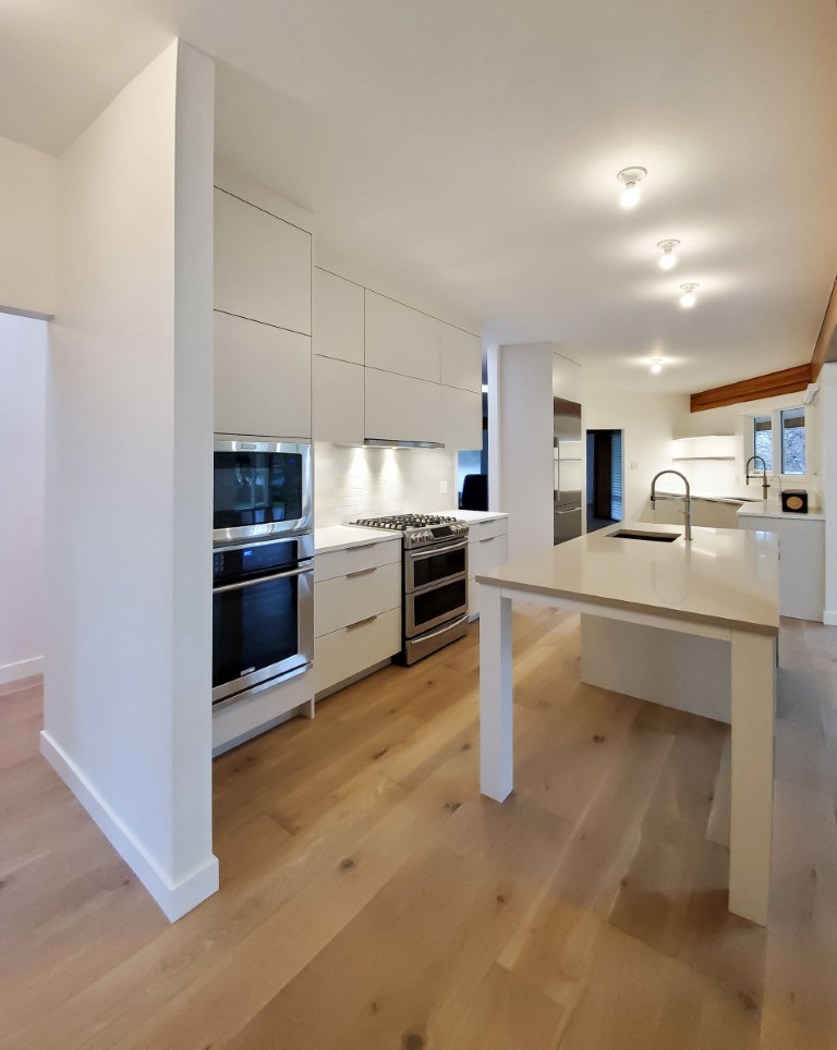 Image of Modern kitchen with white cabinets, stainless steel appliances, and island sink by KHD Homes design-build team.