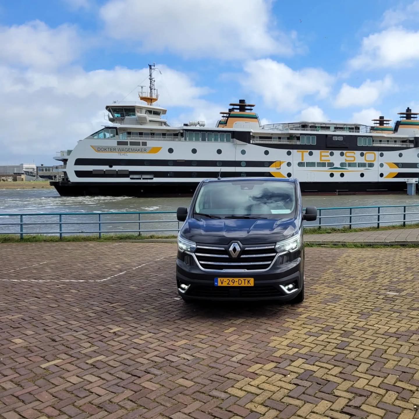 Bovenaanzicht van een Van Ede Koeriers bus rijdend op een rechte weg door het Nederlandse polderlandschap.