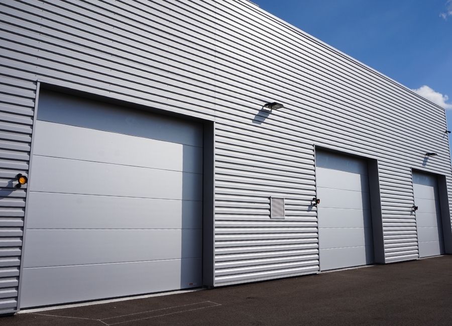 Façade avec bardage ondulé en métal et porte sectionnelle industrielle.